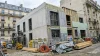 Bâtiment en rénovation avec matériaux de construction et ouvriers.